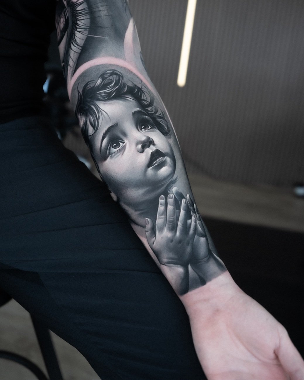 Realism-tatuering av ett barns ansikte och hand på underarmen