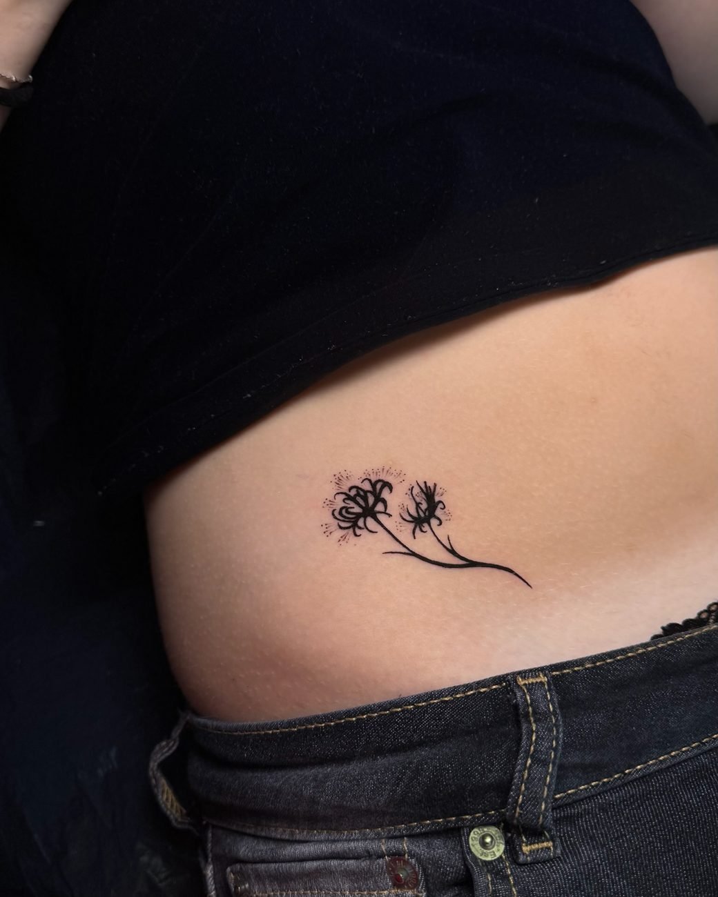 Fine line-tatuering av en maskros på revbenen