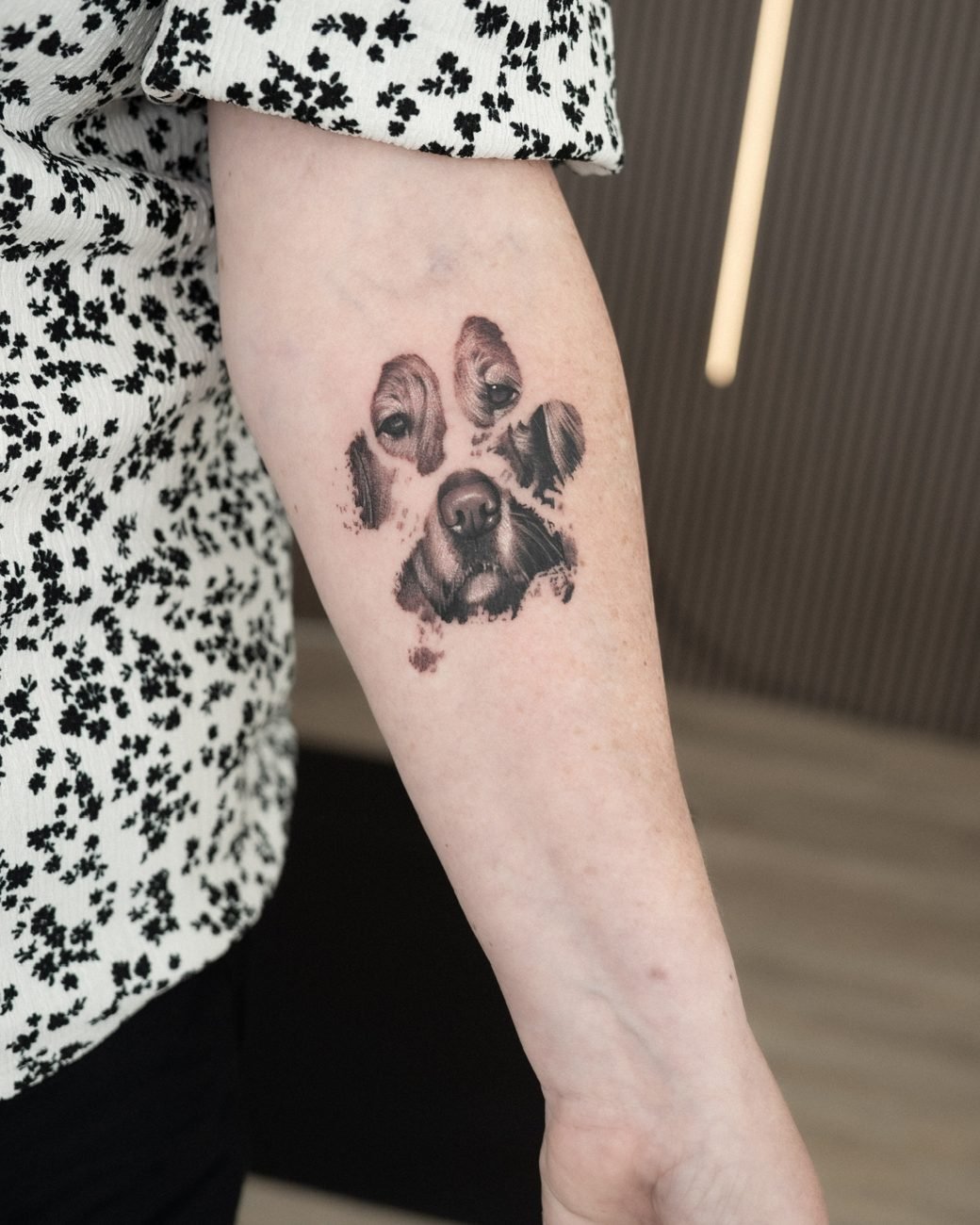 Realism-tatuering av ett tassavtryck med ett hundporträtt på underarmen